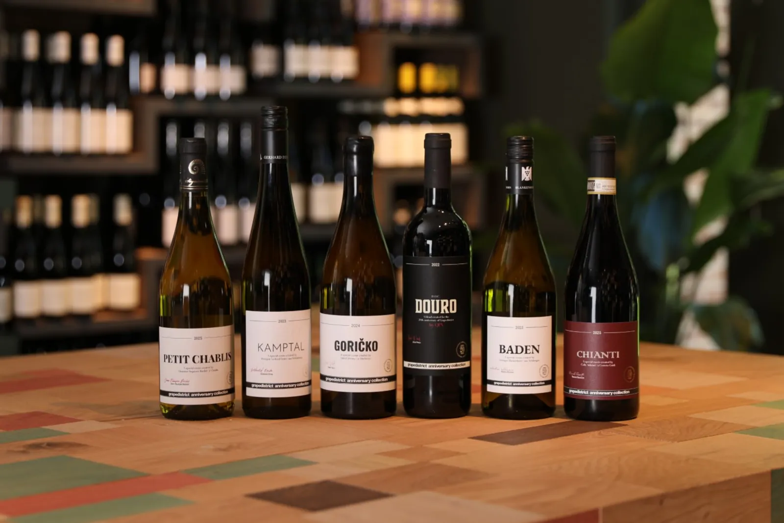 De zes flessen van de Grapedistrict anniversary collection op een kleurrijke houten tafel in de winkel