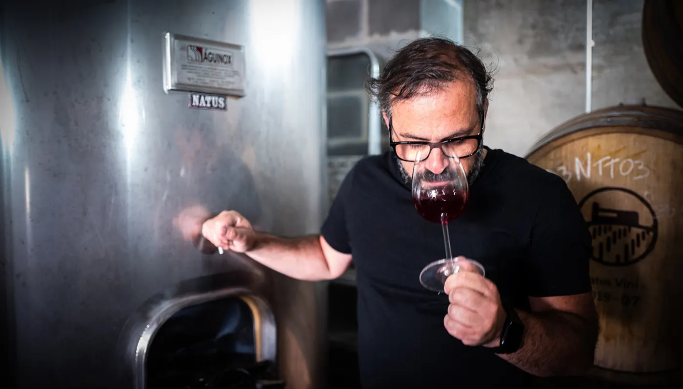 Wijnboer die een glas rode wijn beoordeelt in zijn kelder
