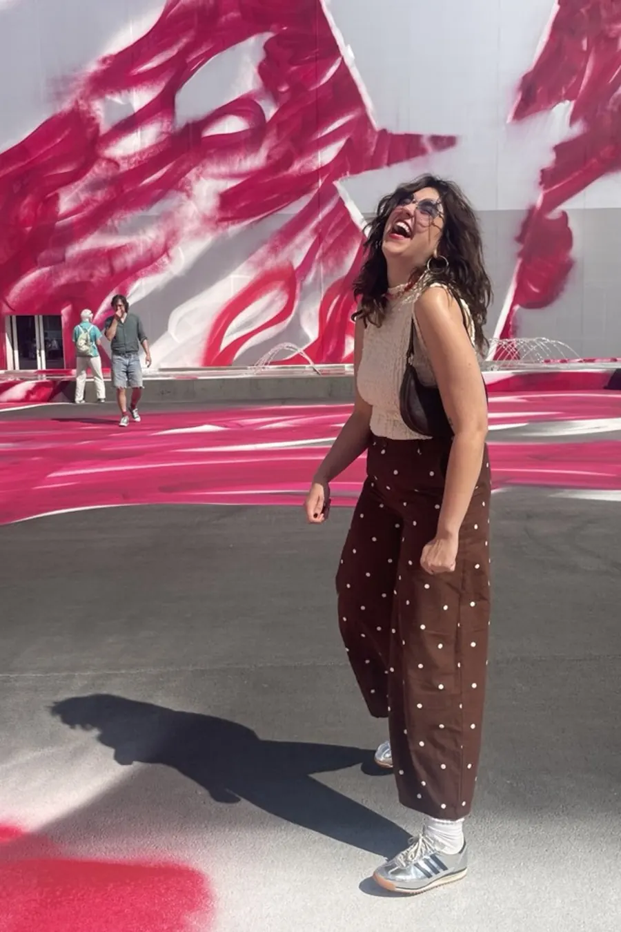 Lola voor een muur met roze graffiti, lachend omhoogkijkend