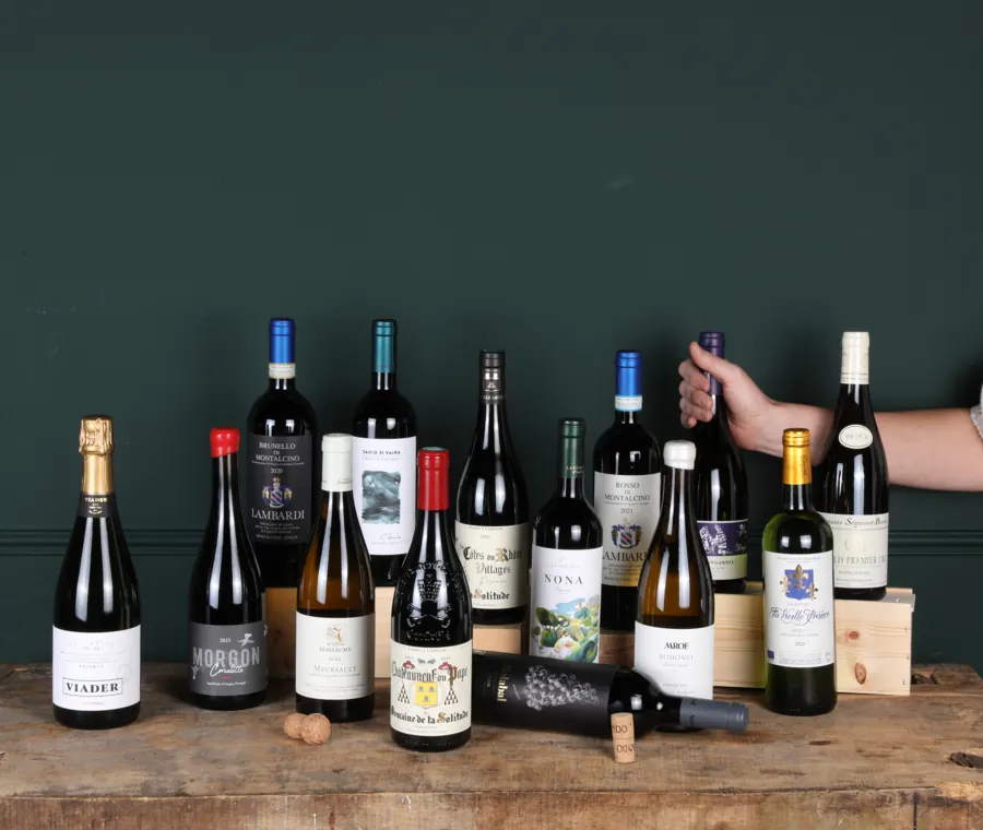 Wijnflessen op een houten tafel voor een donkergroene wand