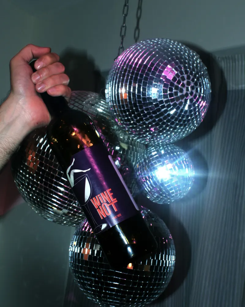 Wijnfles van Wine Not tussen discoballen