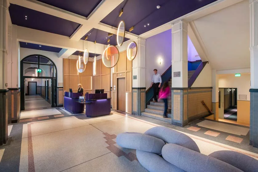 Lobby van The Rebyl met gekleurde vloer, ronde lampen en de originele trap